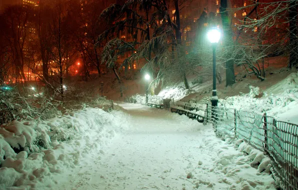 Картинка свет, снег, деревья, город, парк, забор, здания, вечер, фонарь, тротуар